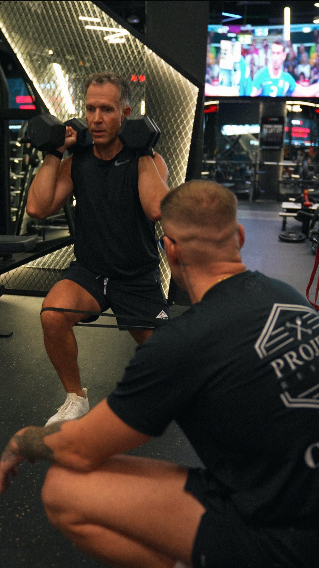 Coach observing a client mid-squat at the studio