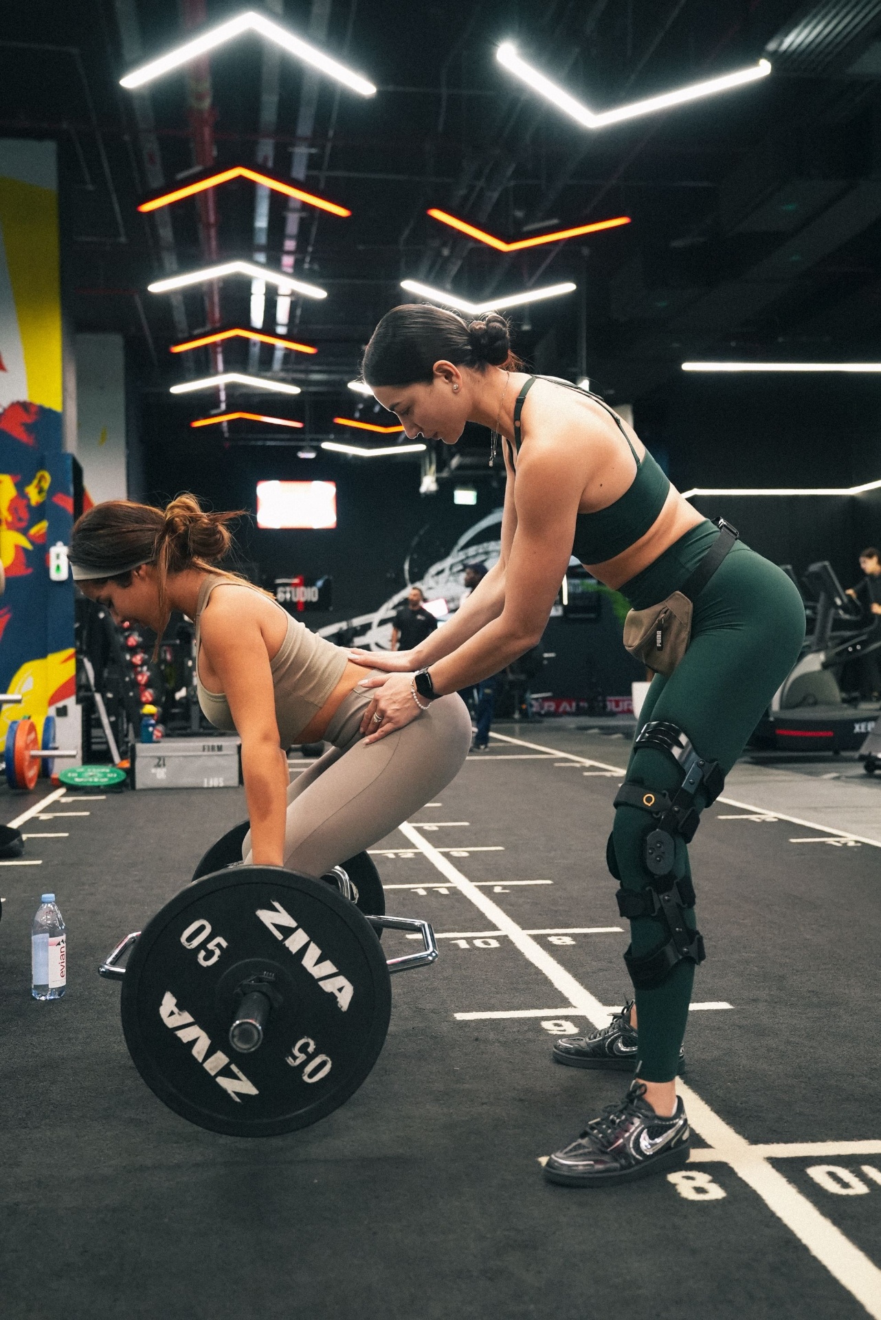 Female Project Reshape coach cueing a client through a deadlift hinge