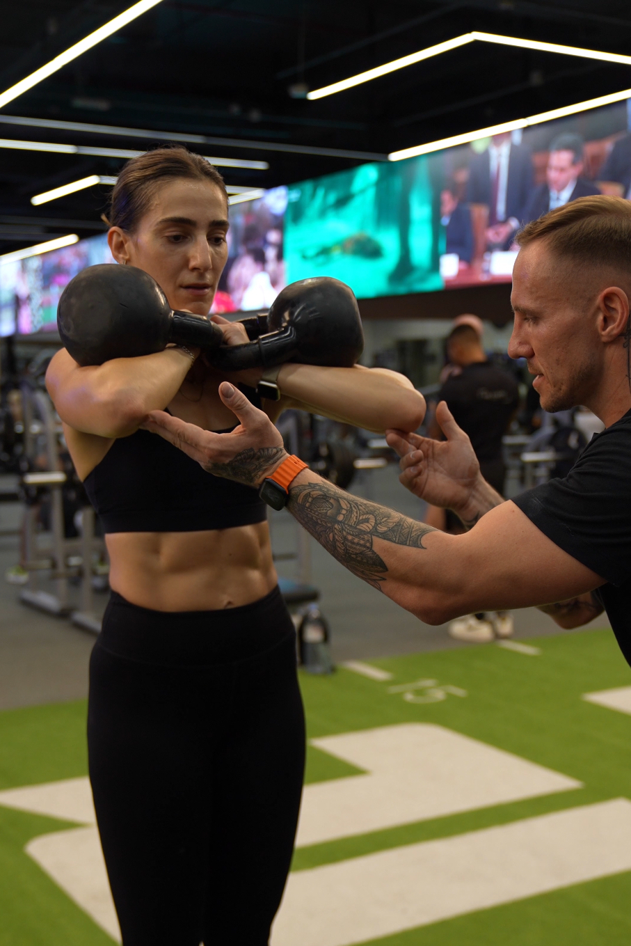 Project Reshape coach guiding a client through a kettlebell front rack